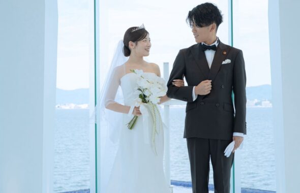 白いシャツに蝶ネクタイを合わせたグリーンのダブルスーツ姿の新郎と、ウェディングドレスの新婦
